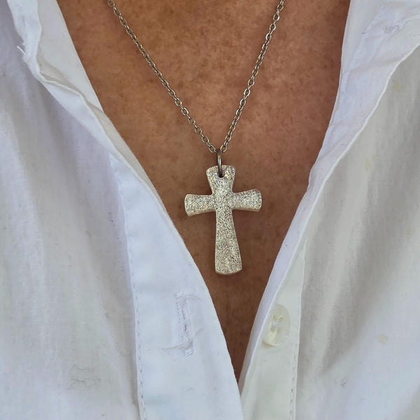 Silver dichroic glass cross pendant held in hand
