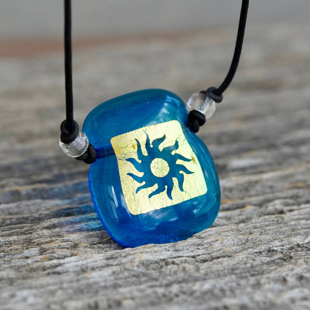 Sun symbol gold on turquoise square dichroic glass pendant