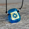 Sun symbol gold on turquoise square dichroic glass pendant