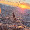Cutout cross bar necklace on a stainless steel box chain set in beach sand at sunset, waterproof cross necklace for men