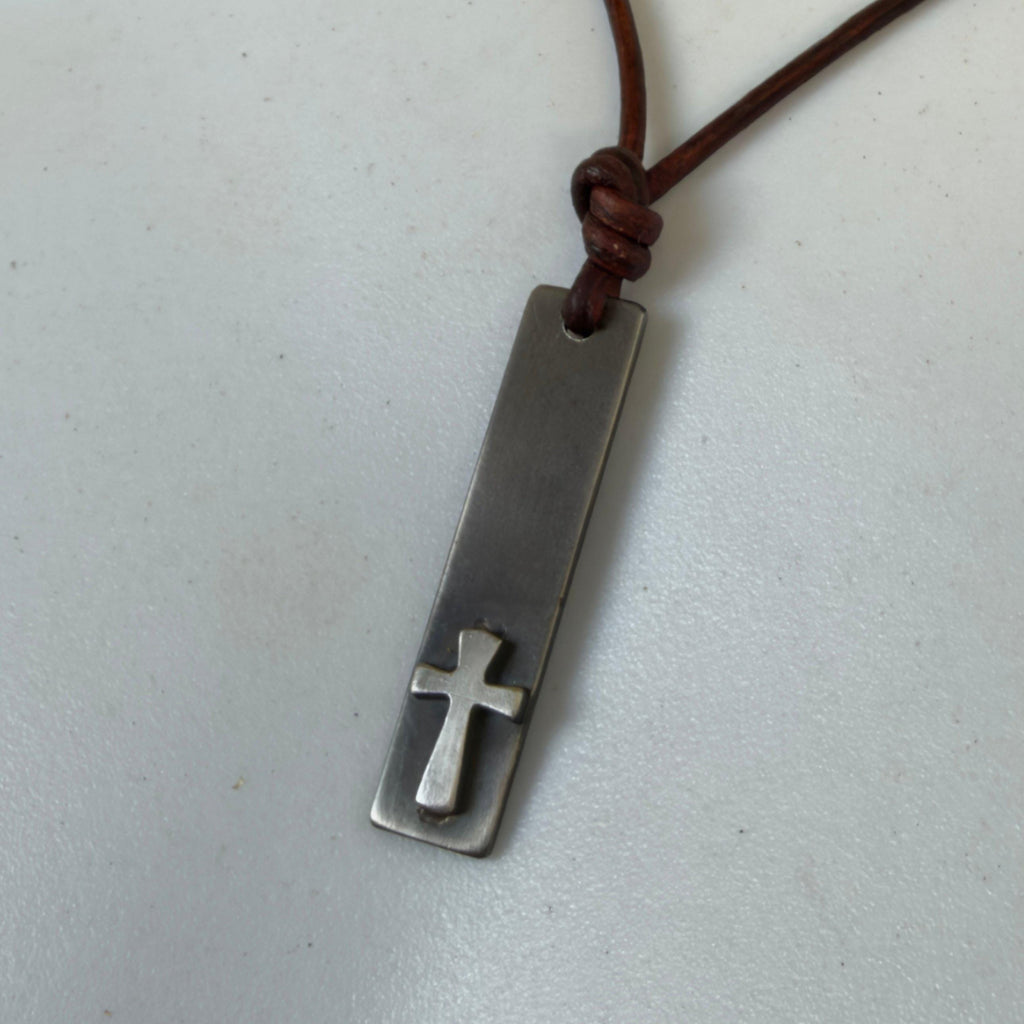 Waterproof stainless steel cross bar pendant for men with a raised silver cross, hanging from a brown leather cord