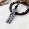 Cross necklace for men, dark stainless steel bar pendant with a cutout cross and coiled brown leather cord on natural linen