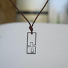Close-up of a men's stainless steel cross necklace on a leather cord, the Breakthrough Cross with an open frame and the cross breaking through the side
