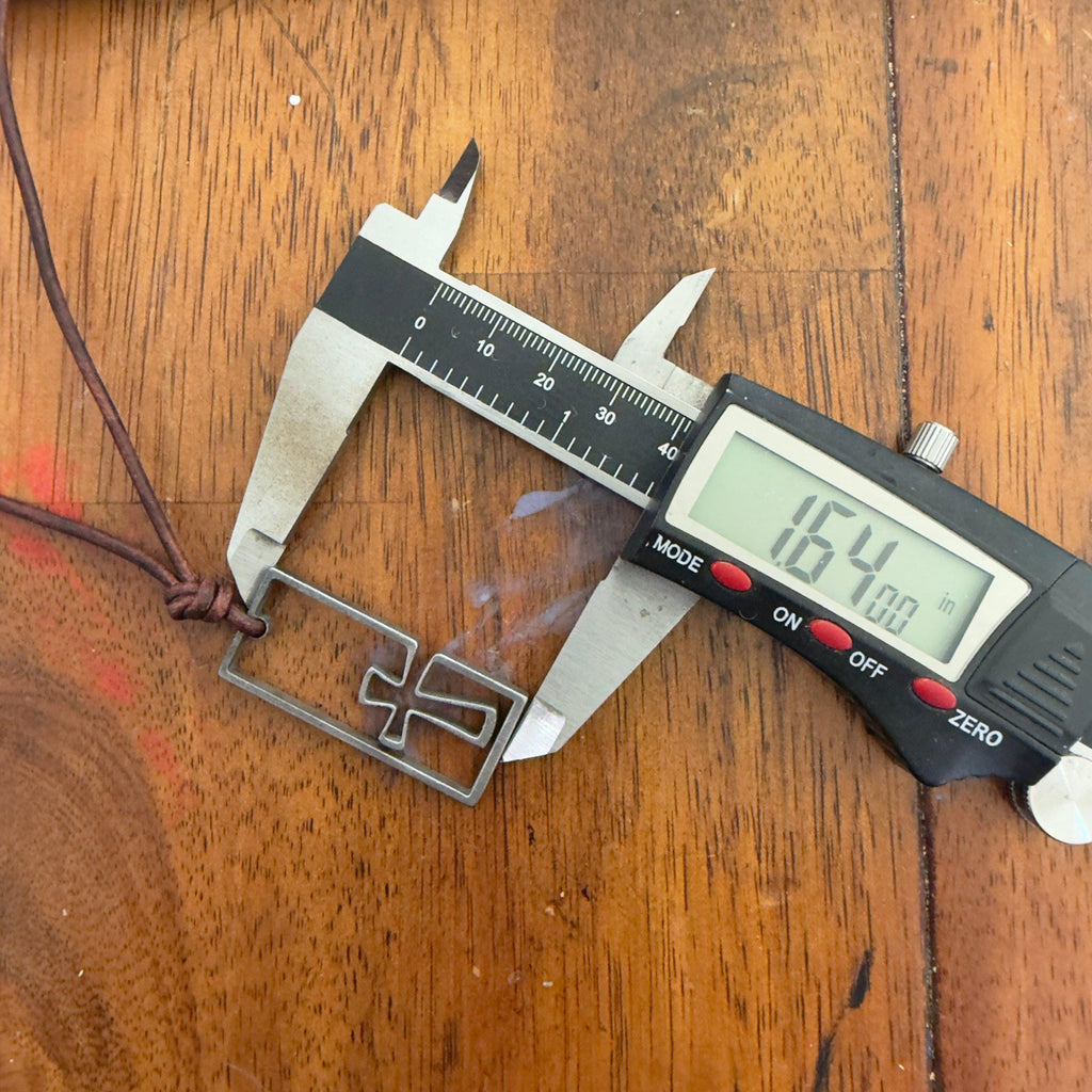 Digital caliper measuring the stainless steel cross necklace pendant at 1.64 inches long, a men's surfer cross on a wooden table