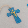 Close up of turquoise fused glass cross ornament showing gold lettering